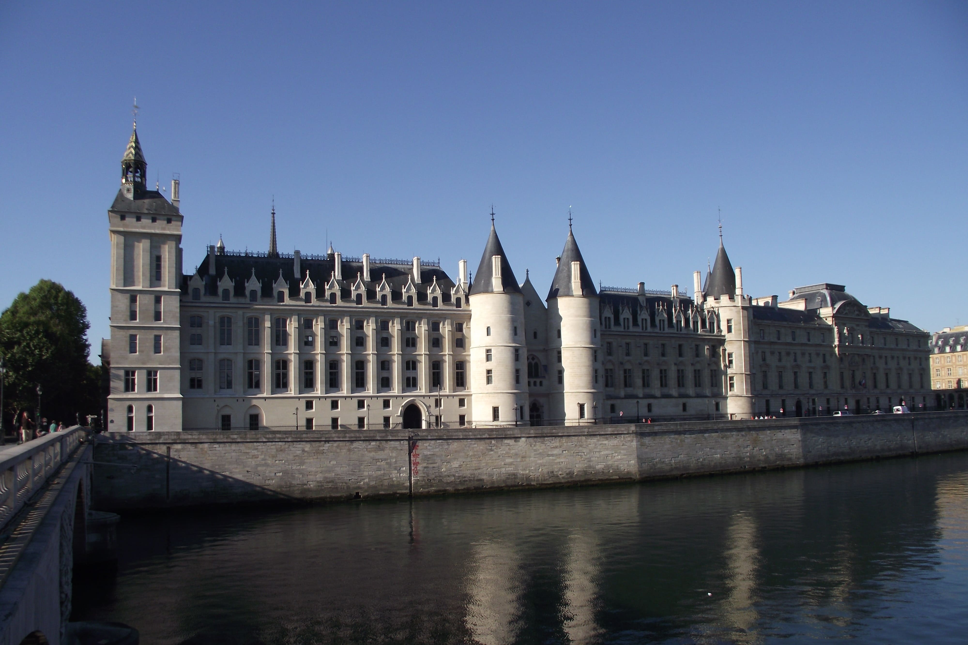 vue sur la façade coté Seine du palais de la cité autrement nommé Conciergerie, avec des reflets des tours dans le fleuve par grand beau temps.