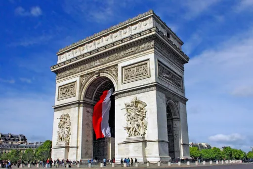L'arc de tromphe parisien avec un drapeau français monumental entre ses arches. Ciel d'été.